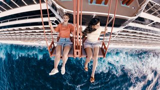 A couple enjoys leisure time while dangling their feet over the side of a cruise ship, surrounded by deep blue sea | MSC Cruises