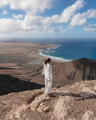 Una mujer está de pie en la cima de una montaña con vistas panorámicas al mar y al paisaje en Lanzarote, España | MSC Cruceros