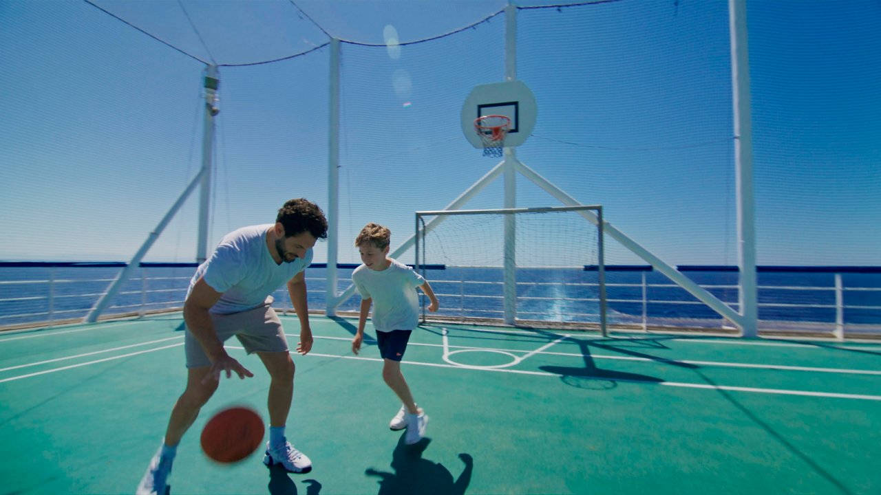 A father and son enjoy a lively game of basketball on the deck of MSC Sinfonia with a stunning sea view | MSC Cruises