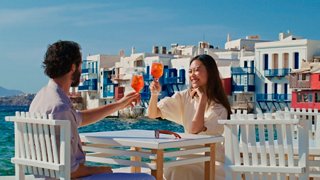 A couple enjoying cocktails and toasting at a bar by the sea in Little Venice, Mykonos | MSC Cruises