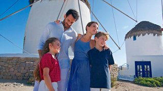 Una familia disfruta de un día soleado juntos cerca de un molino de viento tradicional en Mykonos, Grecia | MSC Cruceros