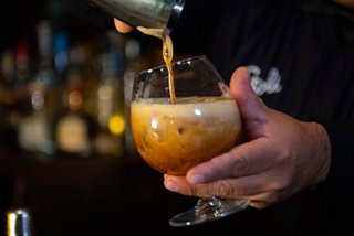 A bartender skillfully pours a Carajillo drink into a glass, showcasing the rich layers and textures of the beverage | MSC Cruises