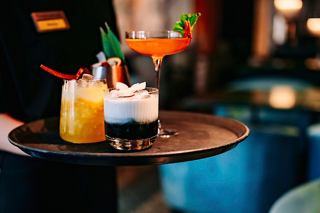 A waiter presents three beautifully crafted cocktails on a tray at Starlight Disco | MSC Cruises