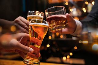 Friends celebrating with a toast, clinking glasses filled with beer in a warm and inviting pub atmosphere | MSC Cruises