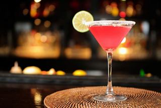 A vibrant cocktail garnished with a lime slice sits elegantly on a woven coaster | MSC Cruises