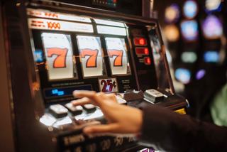 A hand reaches towards a slot machine in the Palm Beach Casino on MSC Armonia | MSC Cruises