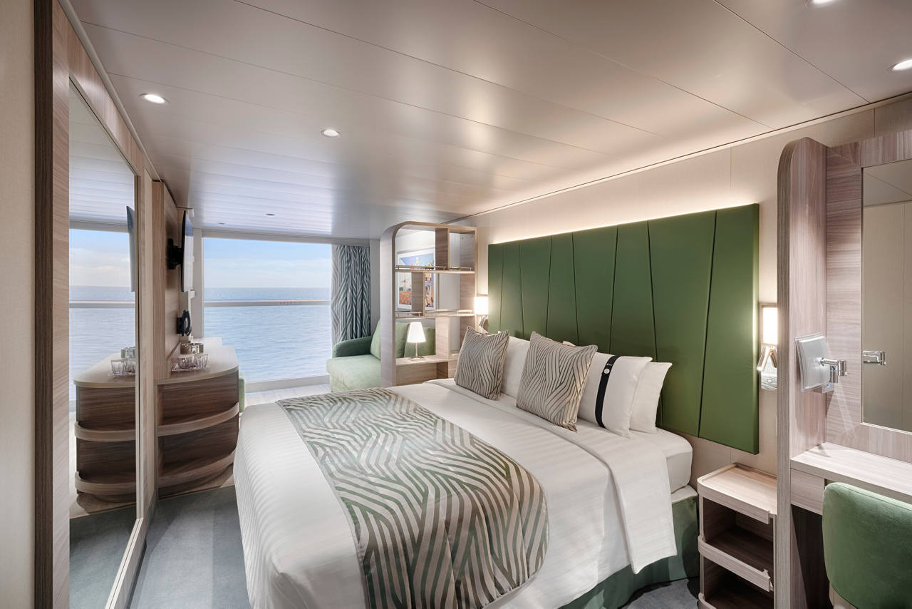 A stylish ocean view cabin featuring a double bed, sofa bed, and vanity area with modern decor | MSC Cruises