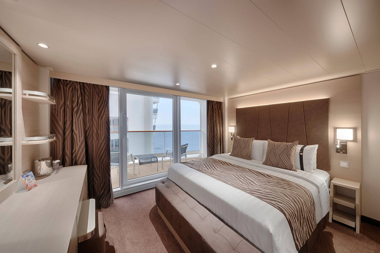 A spacious deluxe balcony cabin featuring a double bed and stunning promenade and ocean views | MSC Cruises