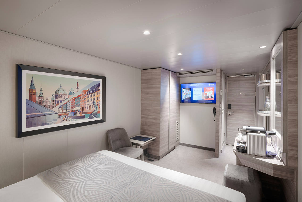 A stylish interior suite featuring a double bed, vanity area, and comfortable seating for a relaxing stay | MSC Cruises