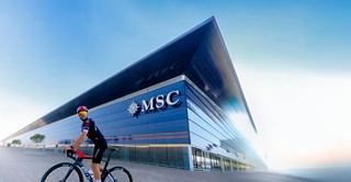 Edificio moderno con fachada de vidrio en Barcelona, junto a un ciclista | MSC Cruceros