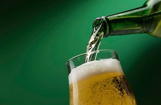 A refreshing beer is being poured into a glass against a green background | MSC Cruises