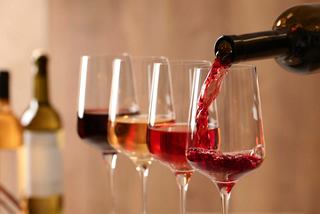 A selection of wine glasses filled with various wines being poured from a bottle | MSC Cruises