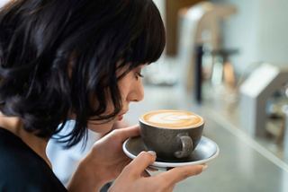 A woman savours a cappuccino in the Armonia Lounge, enjoying a moment of relaxation on board | MSC Cruises