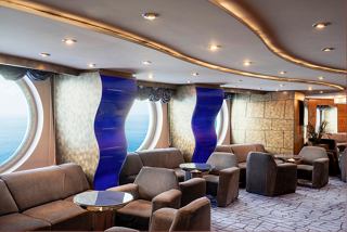 A stylish lounge area with comfortable seating and large portholes showcasing the sea view | MSC Cruises