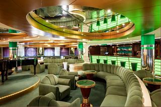 A vibrant lounge area with a bar counter, seating, and a piano inviting relaxation and socialising | MSC Cruises