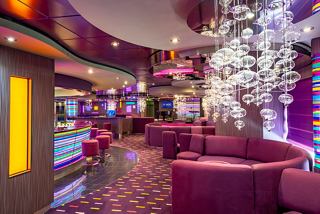 A vibrant lounge area with plush seating, a bar counter, and a stage, inviting guests to relax and enjoy entertainment | MSC Cruises