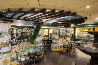 A welcoming bar area with seating, plants, and a fountain, creating a vibrant atmosphere for relaxation | MSC Cruises
