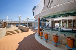 A vibrant outdoor bar area on MSC Splendida with seating and a view of clear skies | MSC Cruises