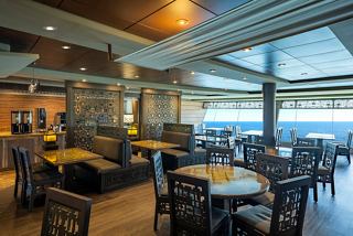 A bright and inviting restaurant space with tables and seating, featuring panoramic sea views | MSC Cruises