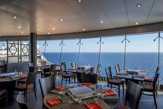 A beautifully arranged dining space with a view of the sea, featuring tables and chairs in the Sea Pavilion | MSC Cruises