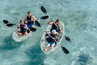 Families enjoy kayaking together in clear waters surrounded by marine life at Ocean Cay MSC Marine Reserve | MSC Cruises