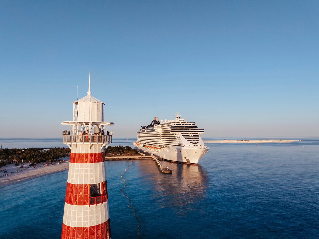 Un faro se encuentra cerca del mar tranquilo mientras un barco de crucero MSC navega hacia Ocean Cay en el Caribe | MSC Cruceros