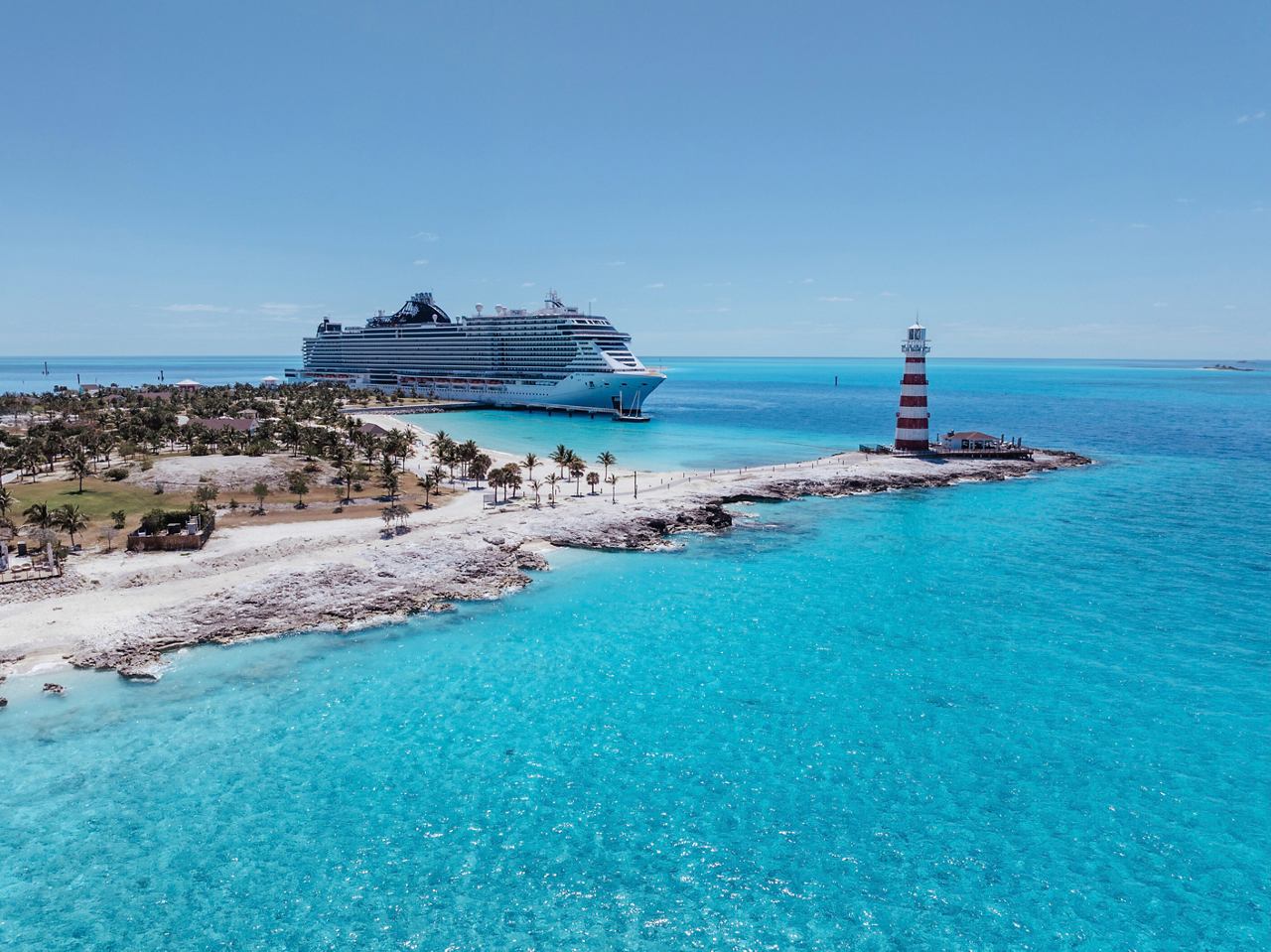 Vista aérea de una hermosa playa con un faro, palmeras y el barco MSC Seashore en el mar Caribe | MSC Cruceros