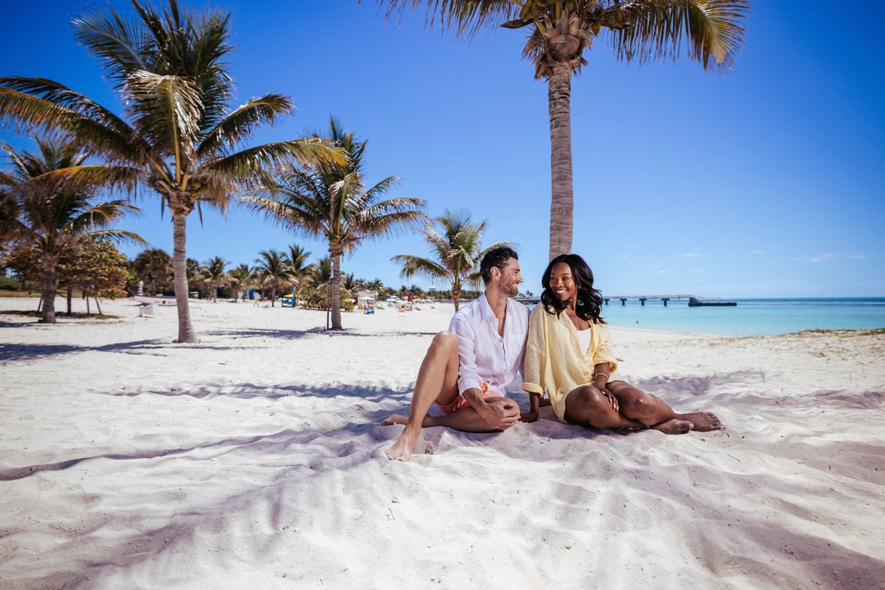 Dos amigos disfrutan de un día soleado en la playa, rodeados de palmeras y un cielo despejado | MSC Cruceros