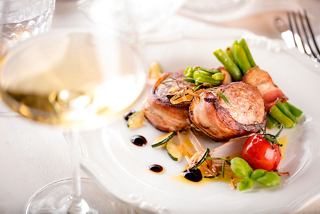 Un plato bellamente presentado con carne, verduras frescas y una copa de vino en el restaurante Posidonia | MSC Cruceros
