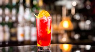A vibrant cocktail featuring orange and strawberry sits elegantly on a bar counter | MSC Cruises