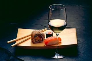 A beautifully arranged sushi platter with chopsticks and a glass of wine, inviting a delightful dining experience | MSC Cruises