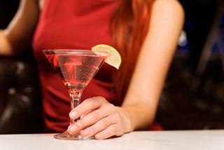 A woman holding a cocktail glass with a lemon slice in a vibrant onboard setting | MSC Cruises