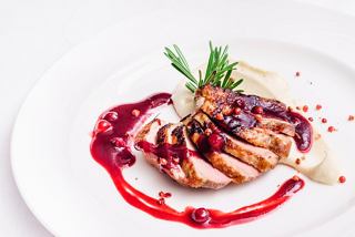 A beautifully plated duck dish drizzled with sauce and garnished, showcasing culinary excellence on MSC Grandiosa | MSC Cruises