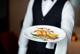 A waiter presents a beautifully plated fish dish, showcasing culinary artistry aboard the MSC Euribia | MSC Cruises