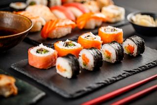 A beautifully arranged selection of sushi including salmon nigiri and rolls served on a dark platter | MSC Cruises
