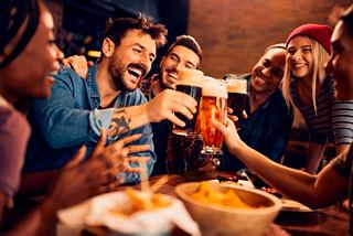 Friends joyfully toasting with beer at a lively gathering, enjoying good food and company | MSC Cruises