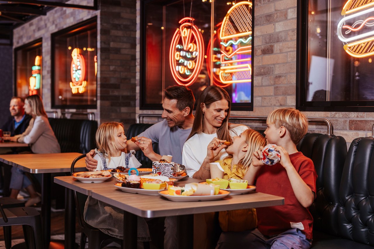 A family enjoys a meal together at a lively restaurant with delicious food on the table | MSC Cruises