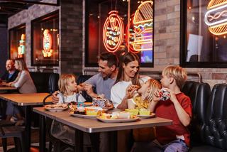 A family enjoys a meal together at a lively restaurant with delicious food on the table | MSC Cruises