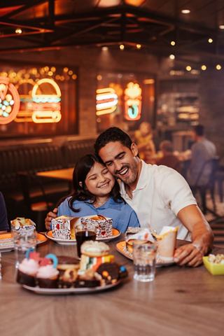 Un père et sa fille partagent un repas dans un restaurant animé à bord du MSC World America | MSC Croisières