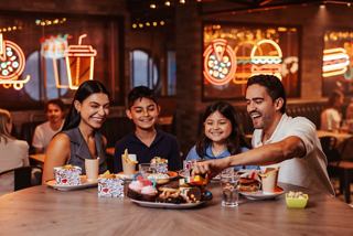 A cheerful family enjoying delicious food together at a specialty restaurant on board MSC World America | MSC Cruises