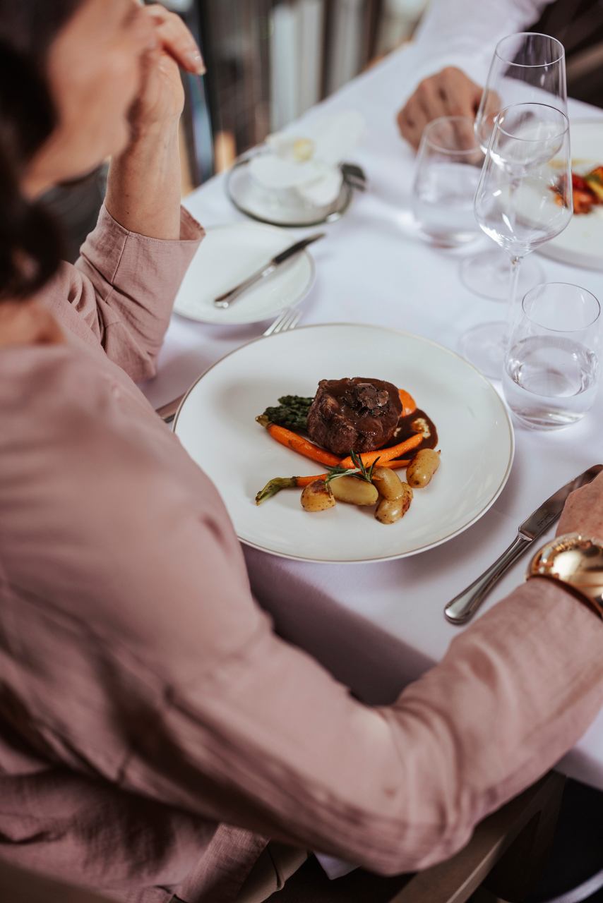 A woman enjoys a beautifully presented main course at the MSC Yacht Club restaurant | MSC Cruises