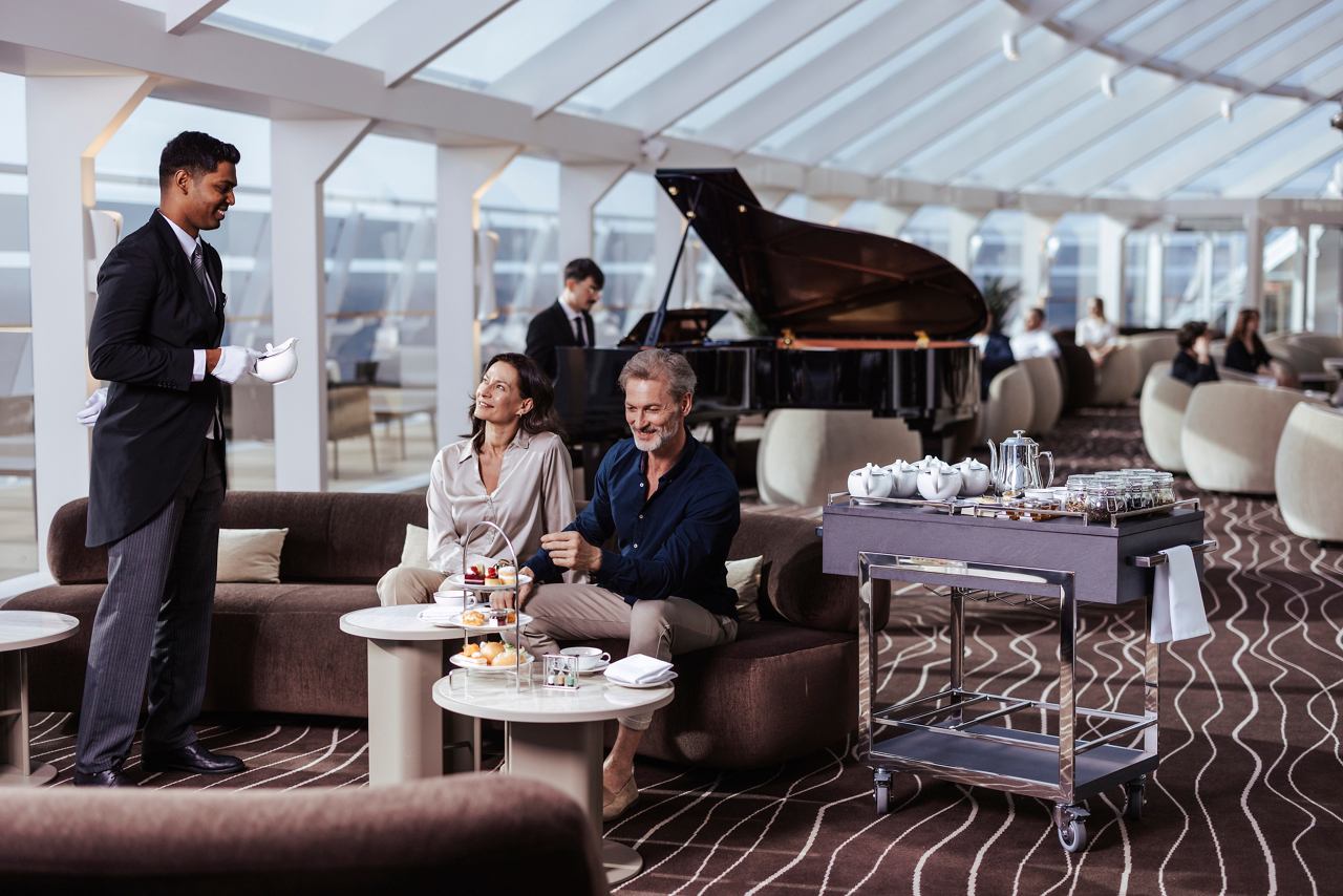 Guests enjoy afternoon tea in the MSC Yacht Club Top Sail Lounge while a pianist plays nearby | MSC Cruises