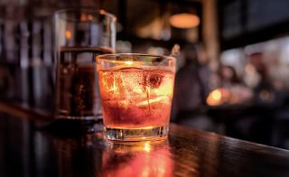 A refreshing cocktail served in a glass, featuring vibrant colours and ice, set against a warm bar ambiance | MSC Cruises