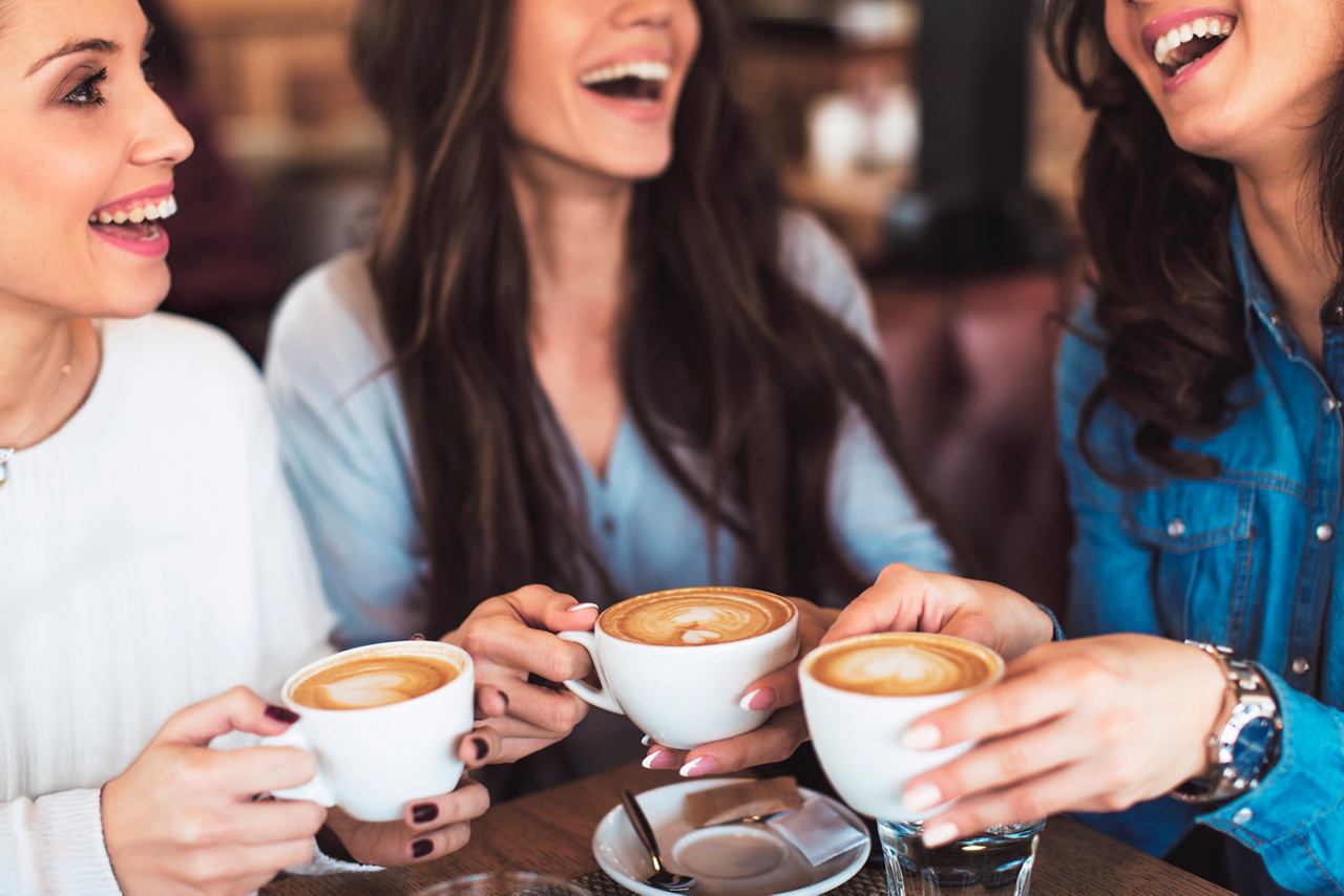 Three women joyfully enjoying cappuccinos together at a coffee bar, creating memorable moments of friendship | MSC Cruises