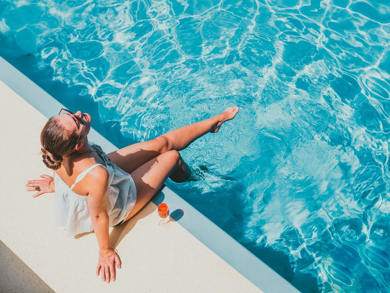 A woman relaxes by the pool while enjoying a refreshing cocktail at Il Bar del Sole on MSC Magnifica | MSC Cruises
