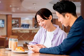 A couple enjoying beverages and a croissant together at the Aroma Coffee Bar on MSC Opera | MSC Cruises