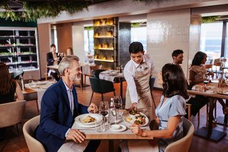 Una coppia si gode un pasto in un ristorante mentre il personale attento serve in un'atmosfera vibrante | MSC Crociere