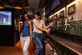 Friends enjoying time together at the bar, pouring drinks and sharing moments in a lively atmosphere | MSC Cruises