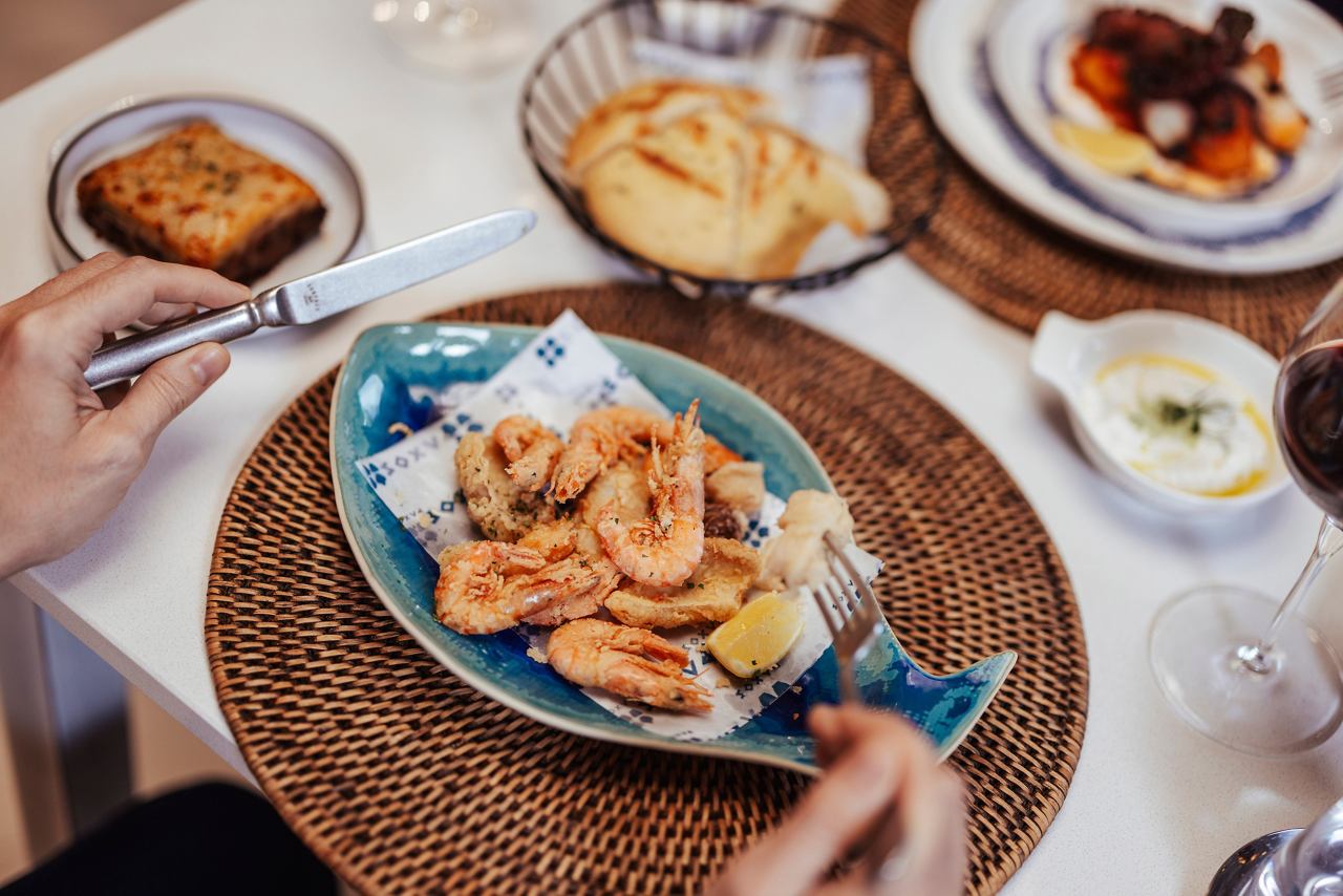 Una coppia gusta un piatto di pesce con gamberi e vino in un ristorante specializzato a bordo di MSC World America | MSC Crociere