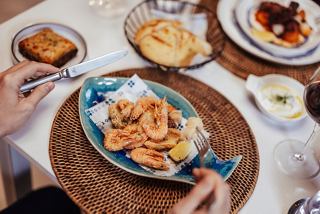 Una coppia gusta un piatto di pesce con gamberi e vino in un ristorante specializzato a bordo di MSC World America | MSC Crociere